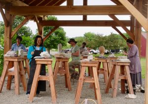 Students working outdoors on stone carving projects during Alkion summer courses