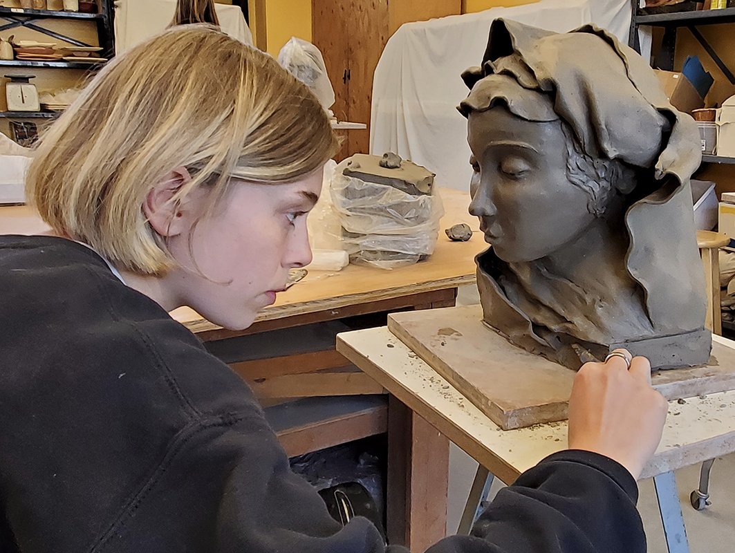 student working on clay sculpture