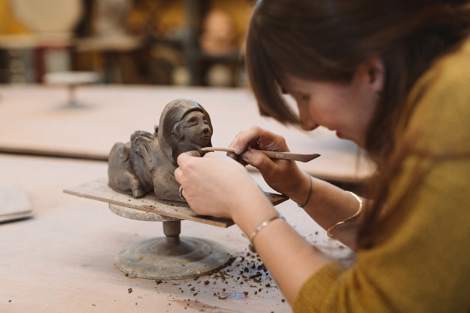 close up of a female student working on a clay sculpture of a sphinx