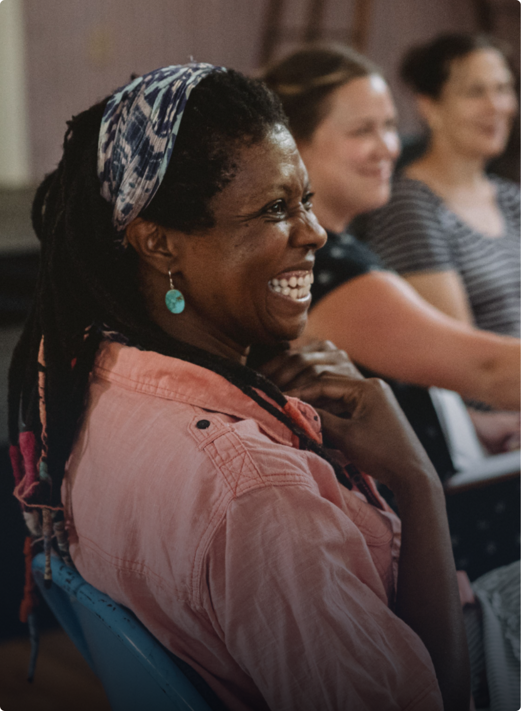 woman laughing, sitting with a group of people in a circle.