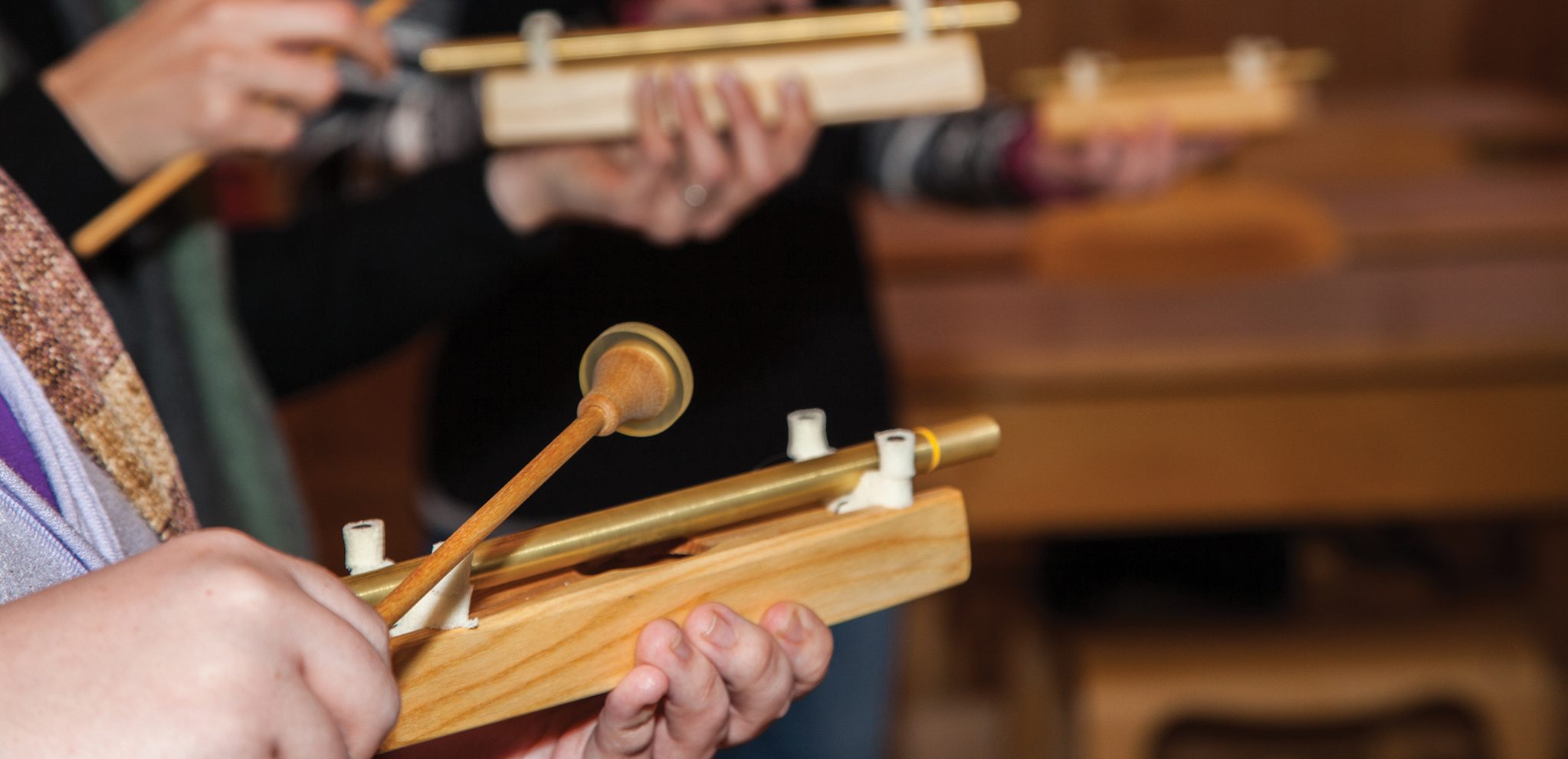 People's hands holding and playing tone pipes.